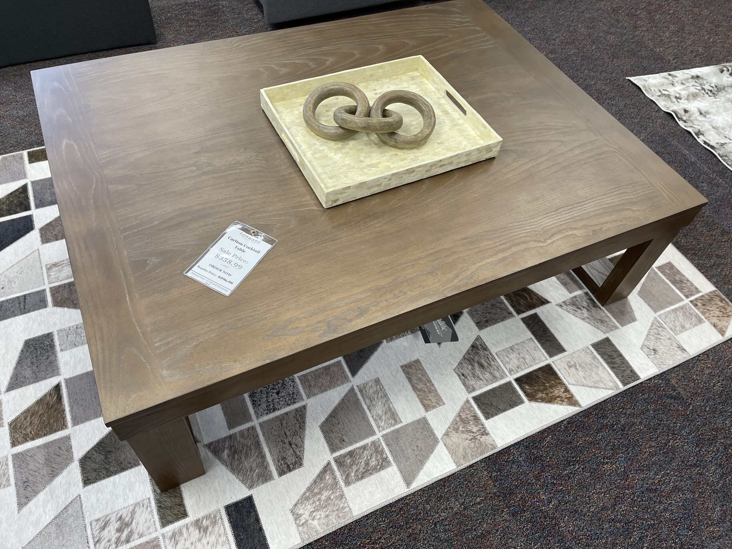 A rectangular Ashley Furniture Galliden cocktail table featuring an aged black rustic finish, thick wood top, and a bowtie-shaped base, available at Forward Furniture Edmonton.