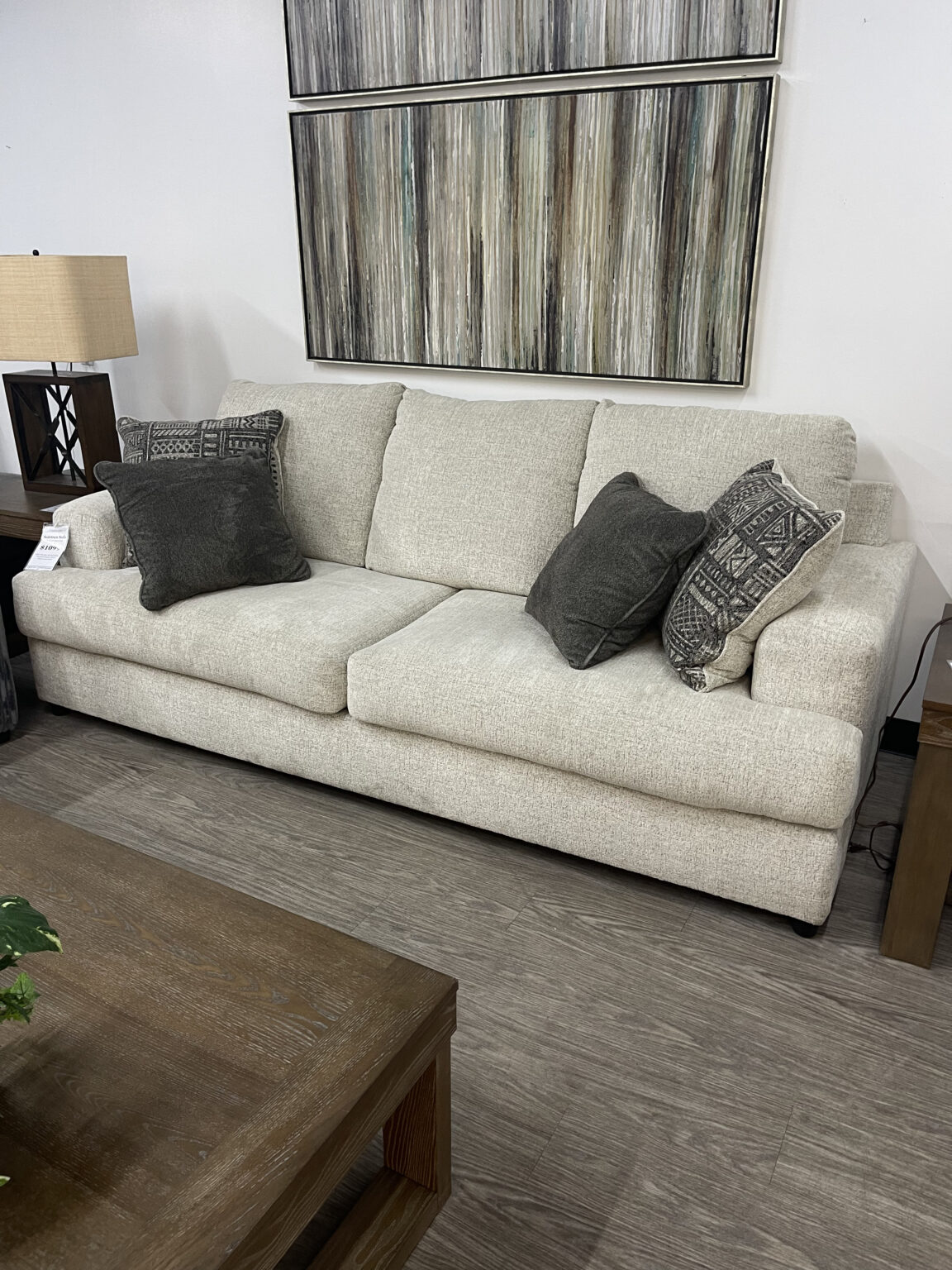 An Ashley Furniture Soletren sofa in "Stone" beige chunky chenille fabric. It features a modern "three over two" design with three attached back cushions over two long, deep seat cushions, finished with exposed faux-wood feet and patterned accent pillows at Forward Furniture Edmonton.