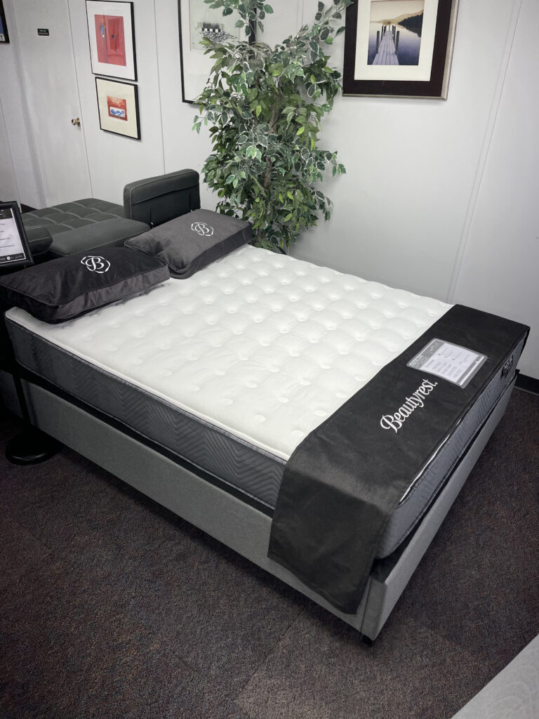A studio shot of the Simmons BackCare Duo mattress, showing the white quilted top and dark grey side panels. The image highlights the 10-inch profile and firm edge support designed for spinal alignment.