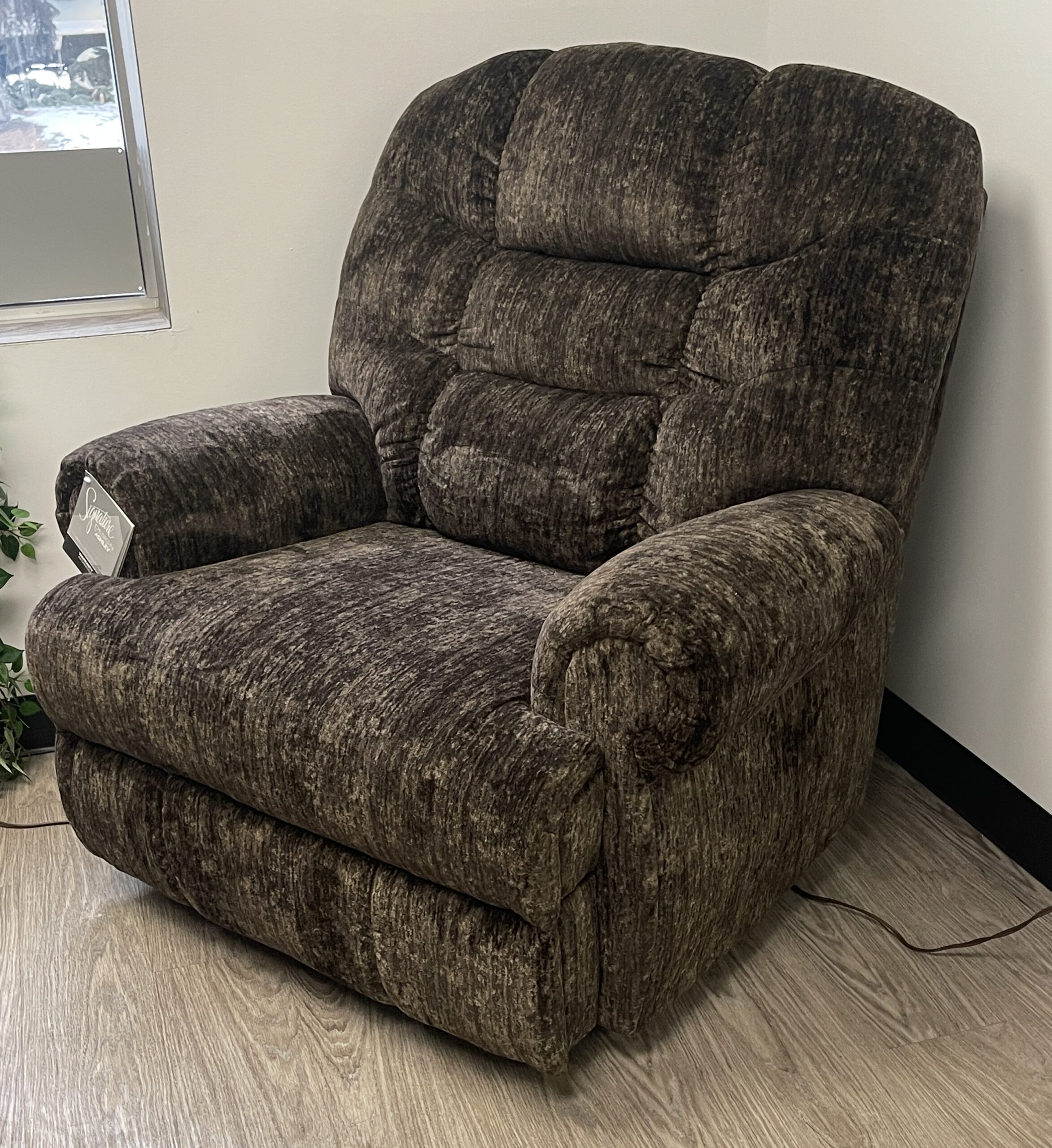An Ashley Furniture Movie Man oversized manual recliner in a rich chocolate-brown plush upholstery. It features a tall, supportive tufted back, deep pillowy cushions, and thick pillow-top armrests, designed for extra comfort and broad support at Forward Furniture Edmonton.